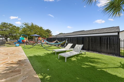 A backyard with a white lawn chair and a playground.