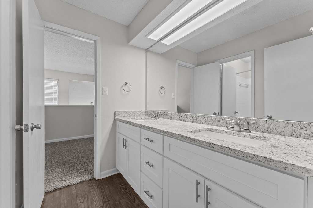A bathroom with a marble countertop and white cabinets.