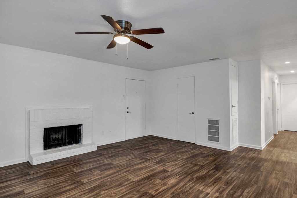 a living room with white walls and a ceiling fan
