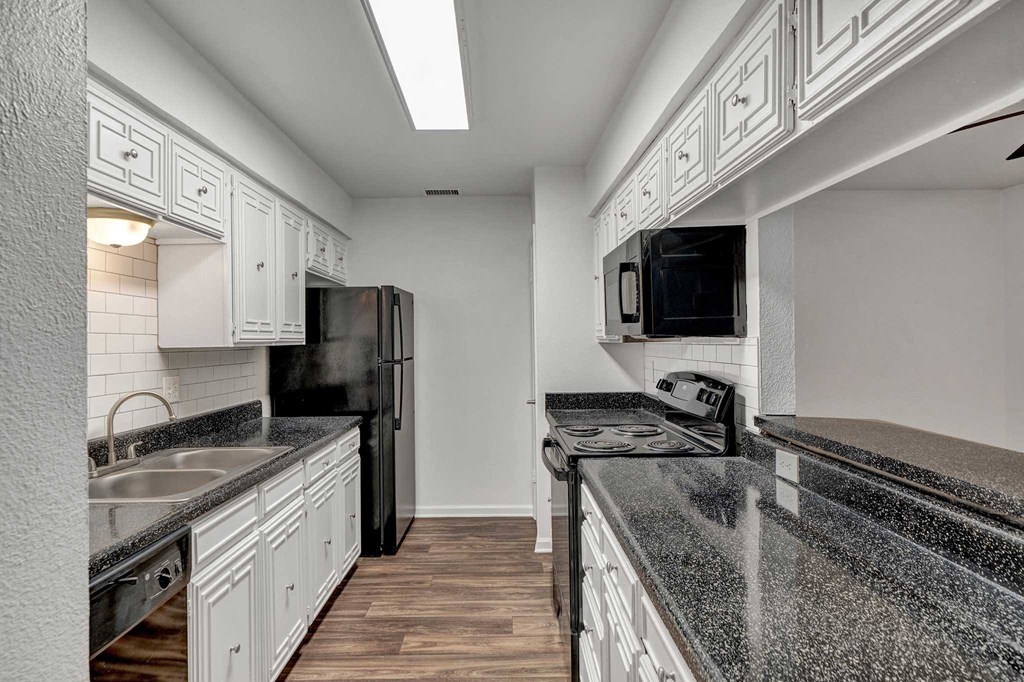 a kitchen with white cabinets and black countertops