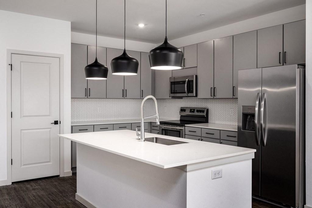a white kitchen with stainless steel appliances and white counter top