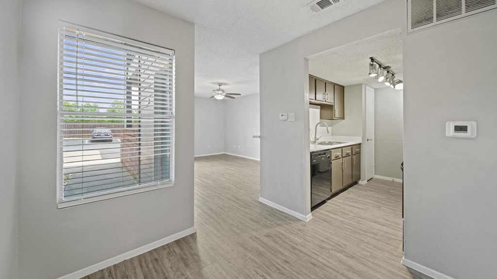 a spacious living room with a kitchen in the background