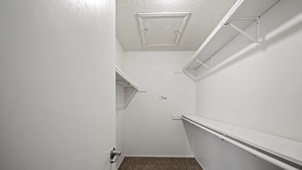 a spacious walk in closet in a bedroom with white walls