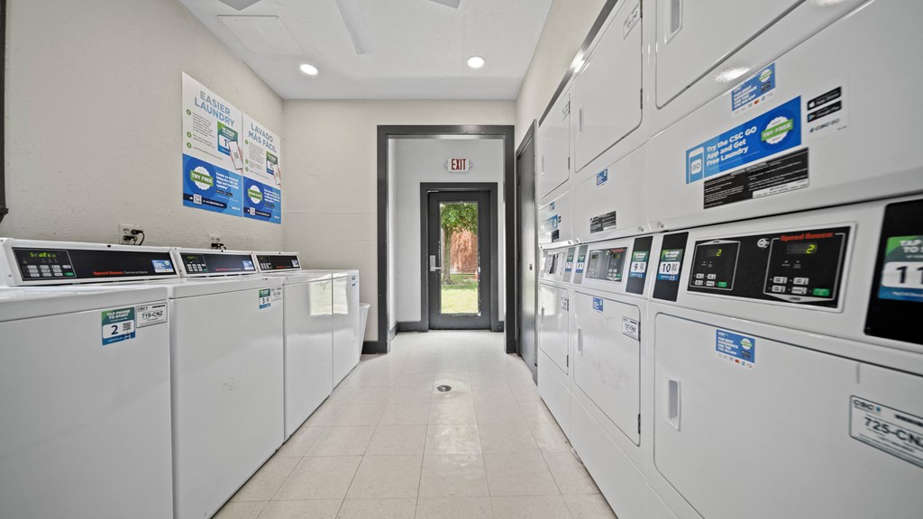 a hallway of washers and dryers with posters on the wall