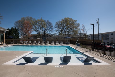 A large outdoor swimming pool with a diving board and lounge chairs.
