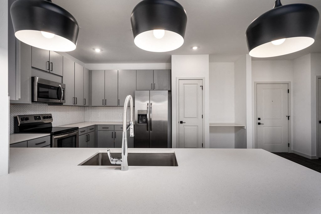 a white kitchen with stainless steel appliances and white counter tops