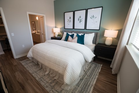 A bedroom with a large bed and a nightstand with a lamp.