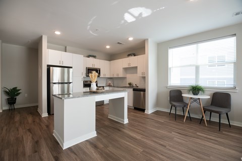 A kitchen with a white island and wooden floors.