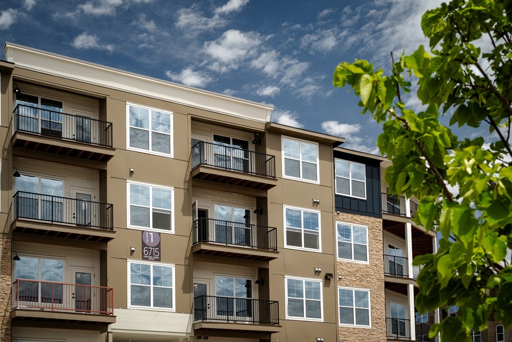 an exterior view of an apartment building with balconies and a tree