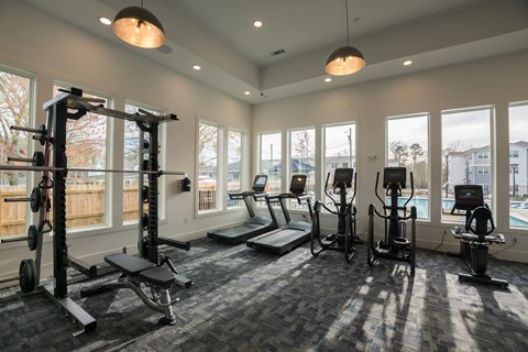 A spacious gym with a variety of equipment including treadmills, stationary bikes, and weightlifting machines.