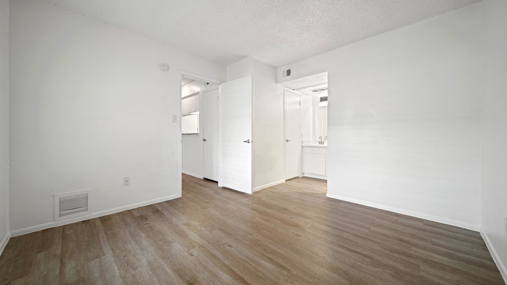 a bedroom with hardwood floors and white walls