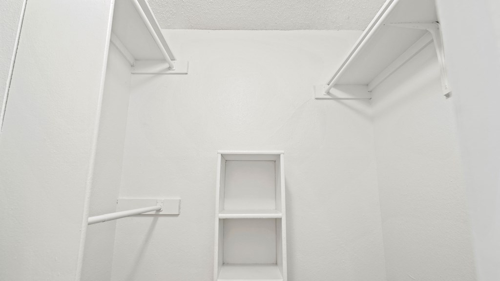 a white wall with two white shelves and a white ladder on the side of the wall