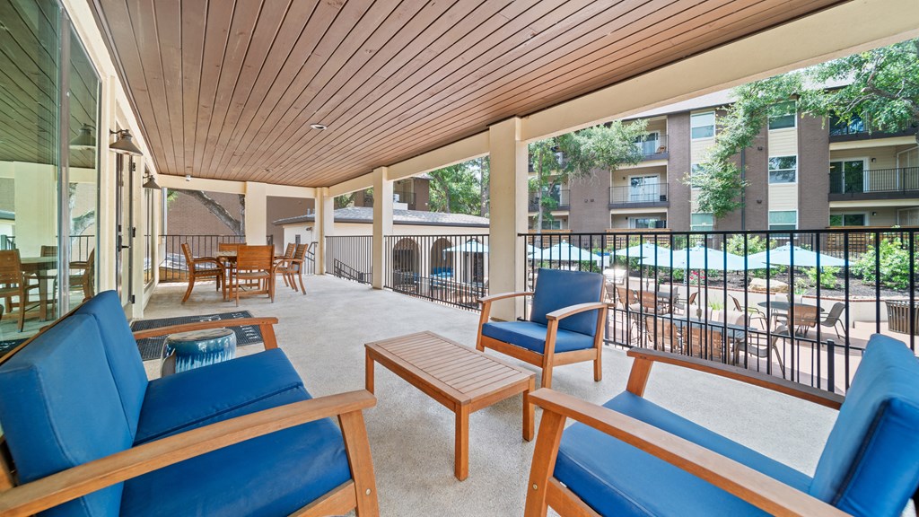 a covered patio with blue chairs and a coffee table