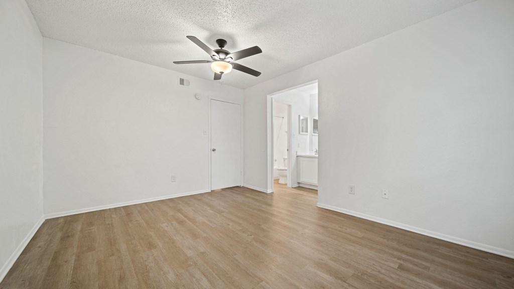 an empty living room with a ceiling fan