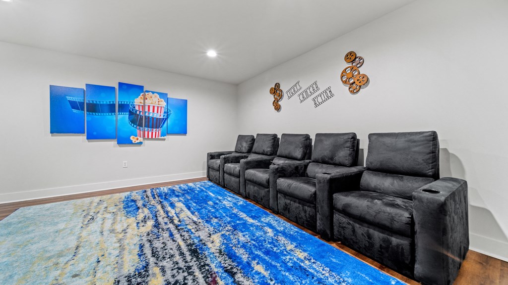 the living room has a large blue rug and black couches