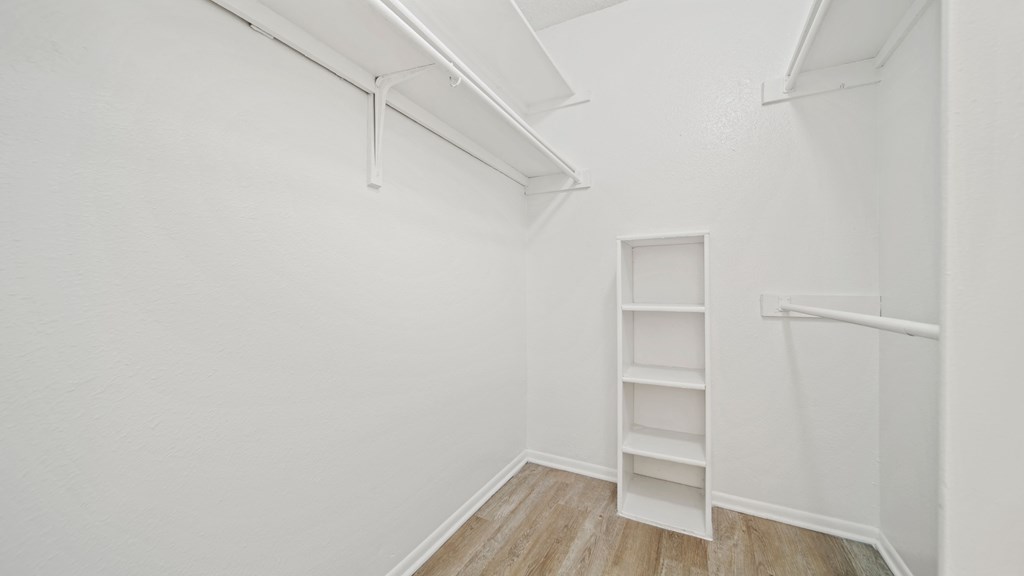 a bedroom with white walls and wood flooring
