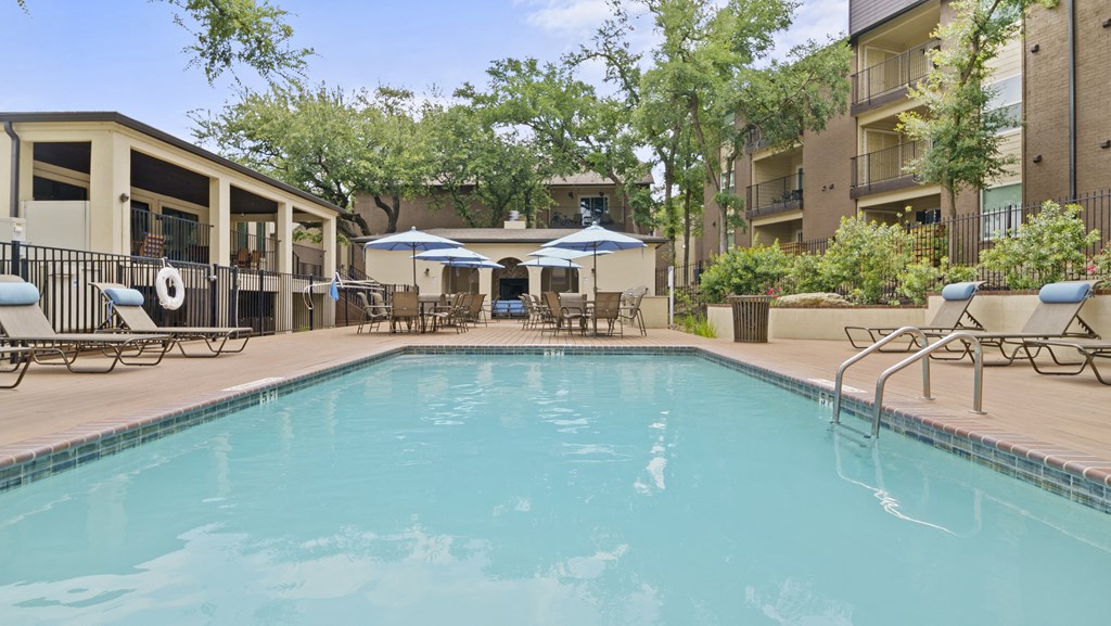 a swimming pool with lounge chairs and umbrellas in front of a building