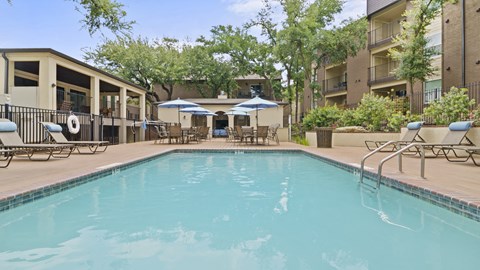 a swimming pool with lounge chairs and umbrellas in front of a building