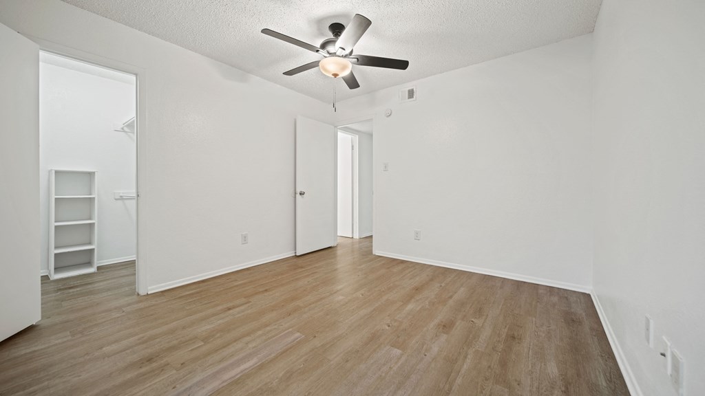 a bedroom with hardwood floors and white walls