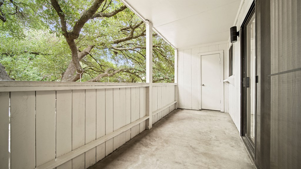 a long porch with a door and trees in the background