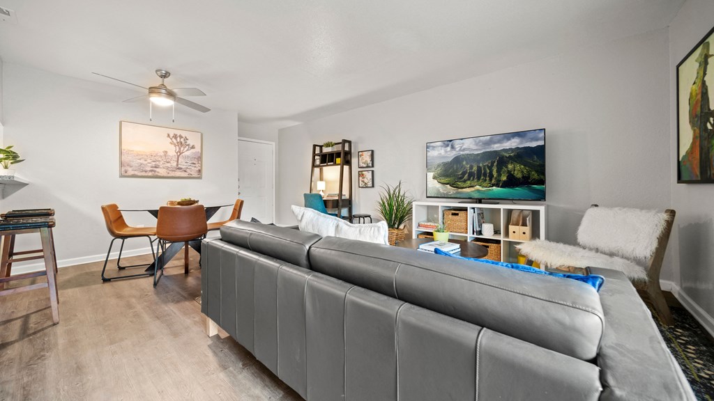 a living room and dining room with white walls and a ceiling fan