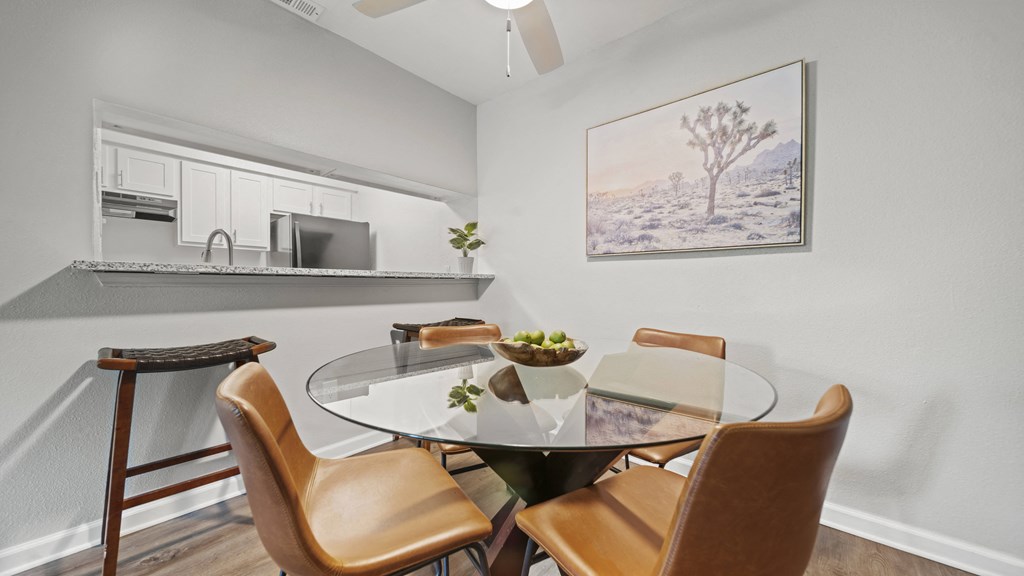 a dining area with a glass table and four chairs