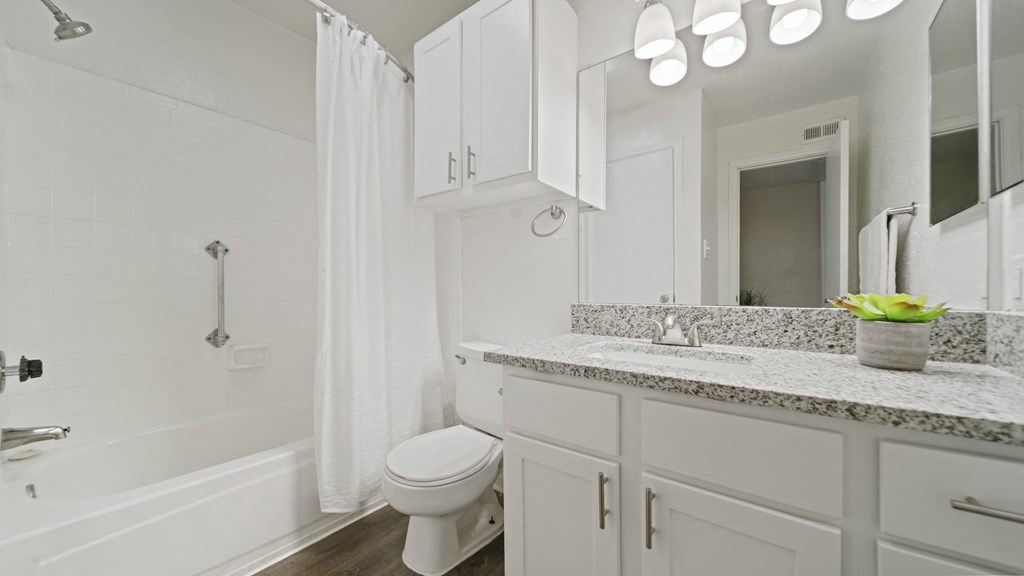 a bathroom with white cabinets and a white bathtub