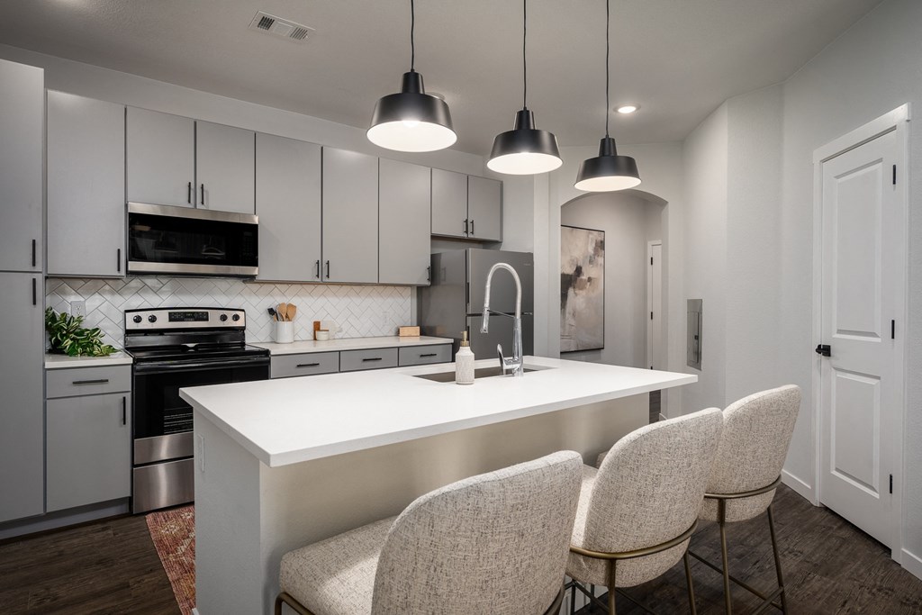 a kitchen with white cabinets and a white island with four chairs