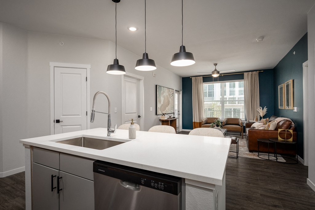 view of living room from kitchen of model home with white counter top and a sink