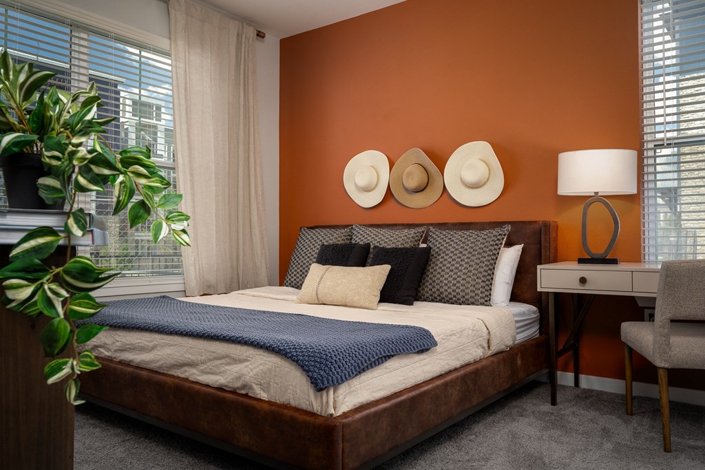 a bedroom with an orange wall and a bed with hats on it