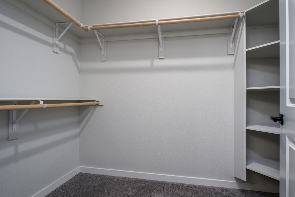 a walk in closet with shelves and a hanger on the wall
