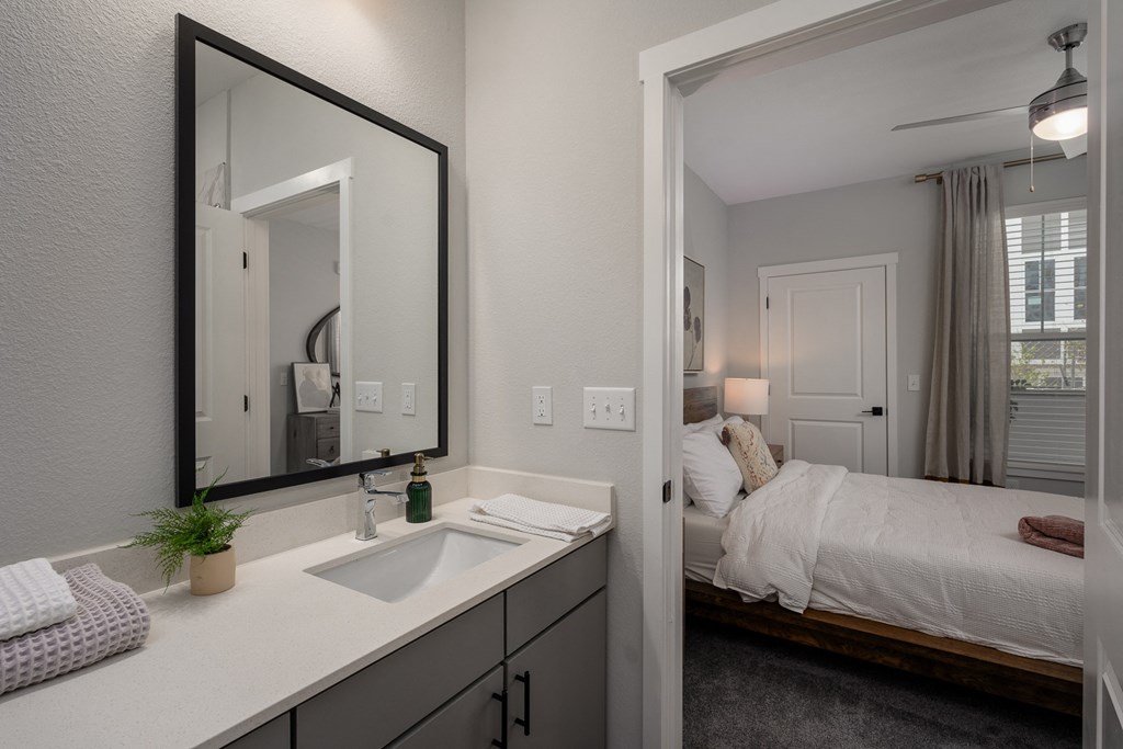 a bathroom with a mirror and a sink and a bedroom with a bed