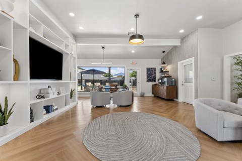 A modern living room with a grey rug on the floor and a flat screen TV mounted on the wall.