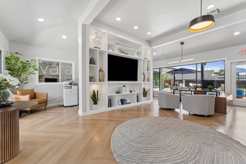 A modern office lobby with a reception desk, seating area, and a large window overlooking the outside.