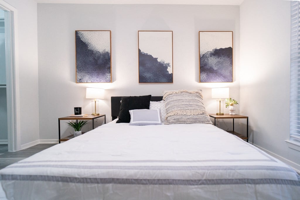 a bedroom with a white bed and three paintings on the wall