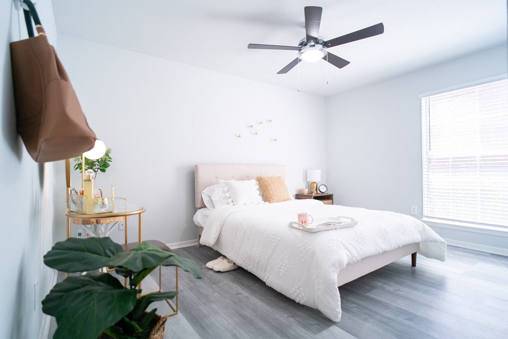 a bedroom with a white bed and a ceiling fan