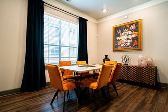 a dining area with a table and chairs and a large painting on the wall