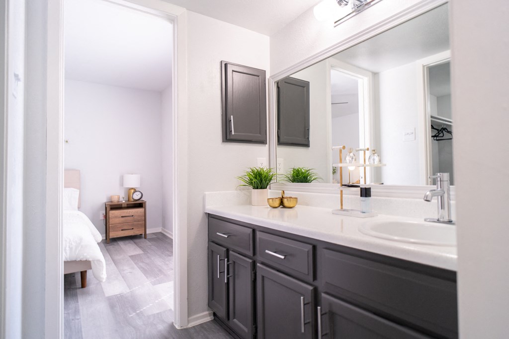 a white bathroom with black cabinets and a large mirror