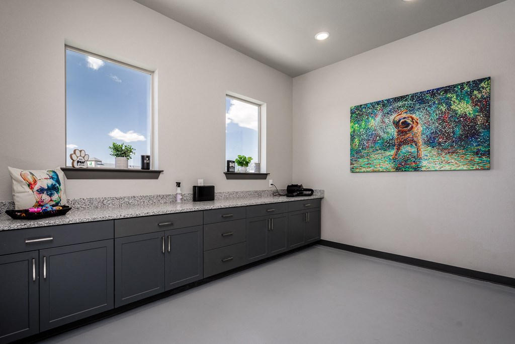 a kitchen with gray cabinets and a painting of a dog on the wall