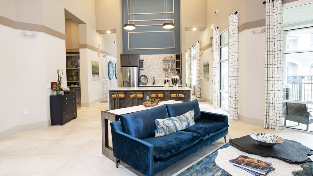 a living room with a blue couch and a kitchen in the background