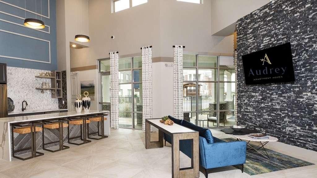 a living room with a blue couch and a kitchen with a counter and glass doors