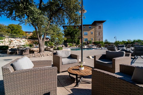 A patio with brown wicker furniture and a tree.
