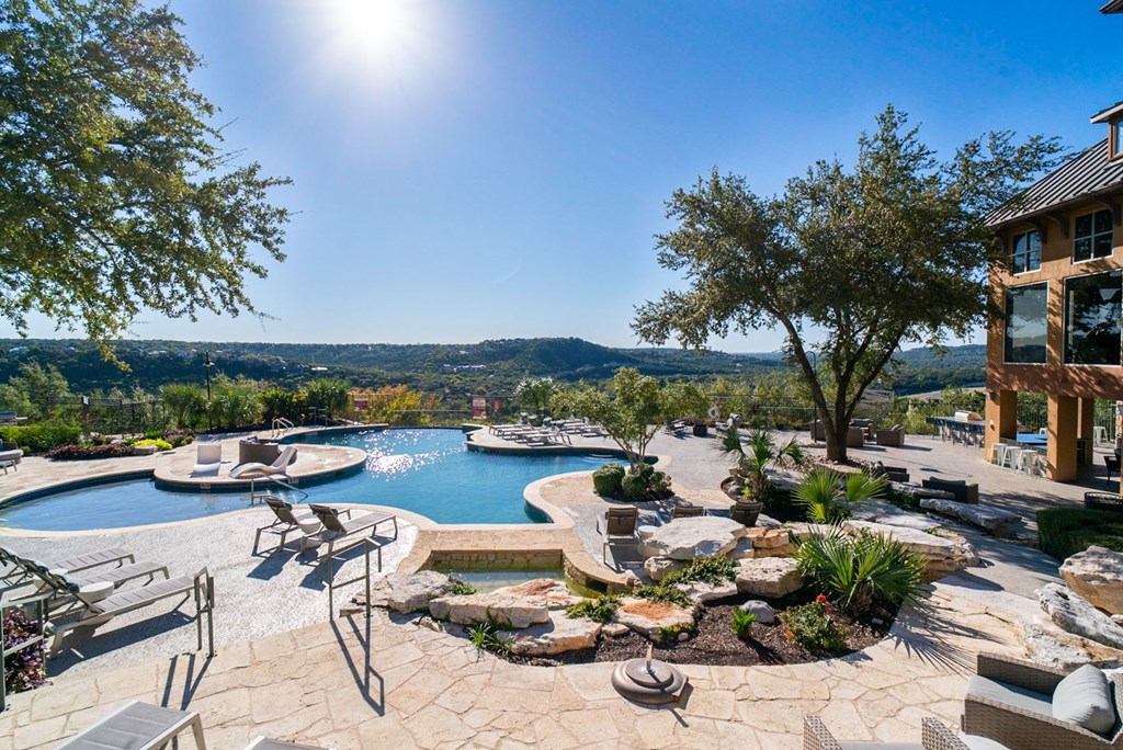 a backyard with a swimming pool and a resort style pool and spa