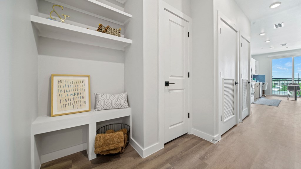 a hallway with a white door and white walls and a white bench with a basket on it