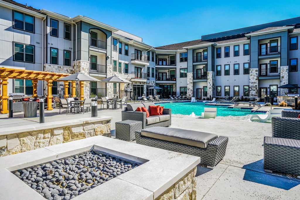 an outdoor amenities area with a fire pit and a swimming pool at an apartment complex