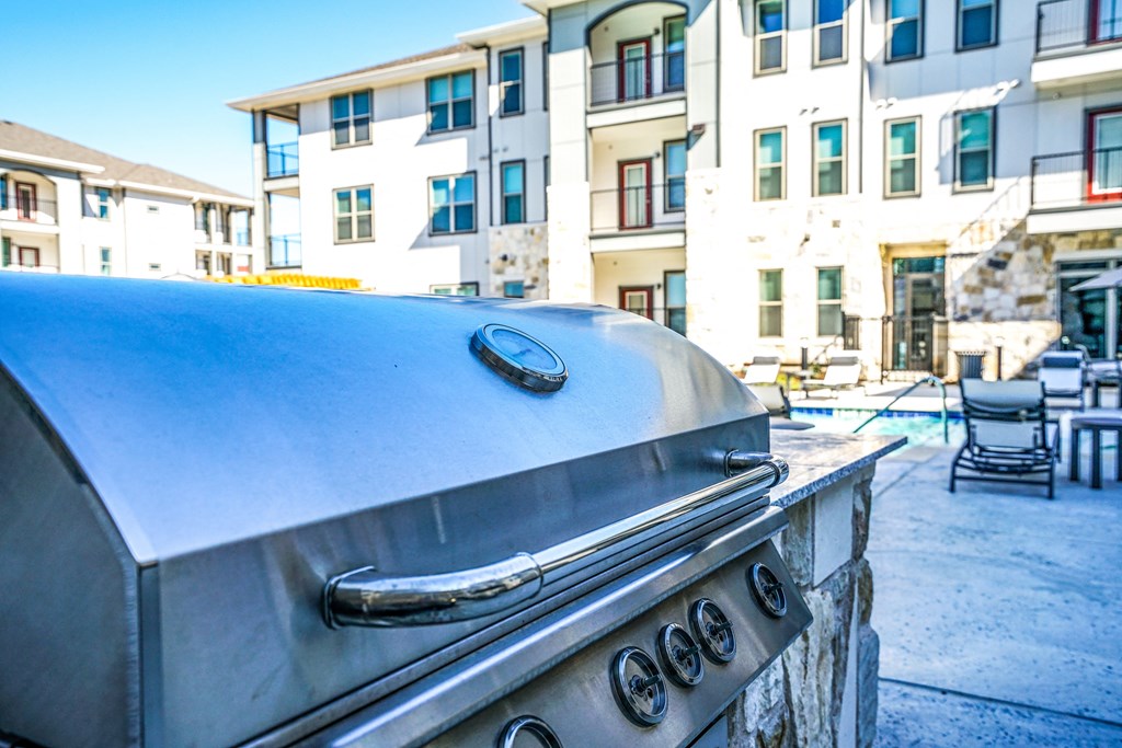 a grill in a backyard with an apartment building in the background