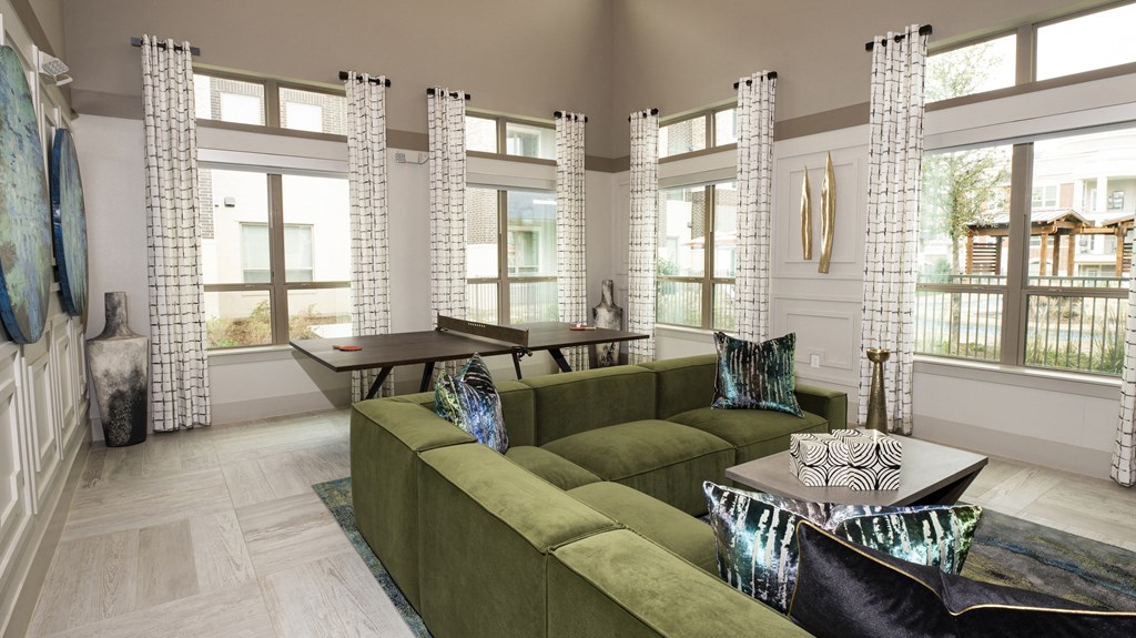a living room with a green couch and a table and windows