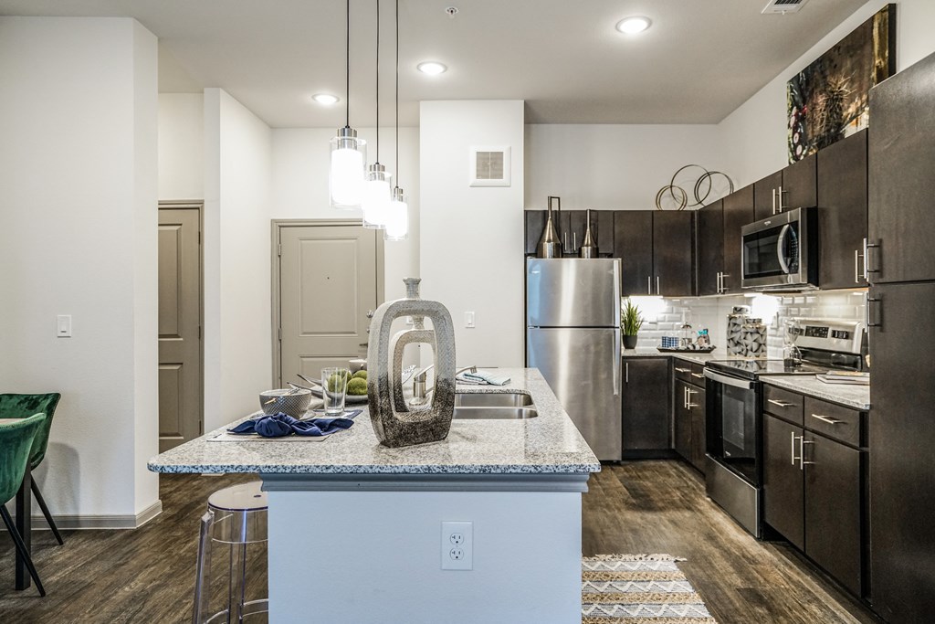 an open kitchen with stainless steel appliances and a granite counter top