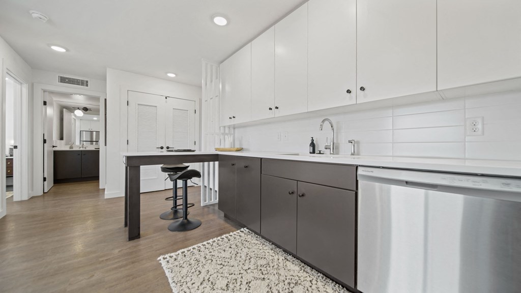 a kitchen with white cabinetry and a gray island with a black countertop