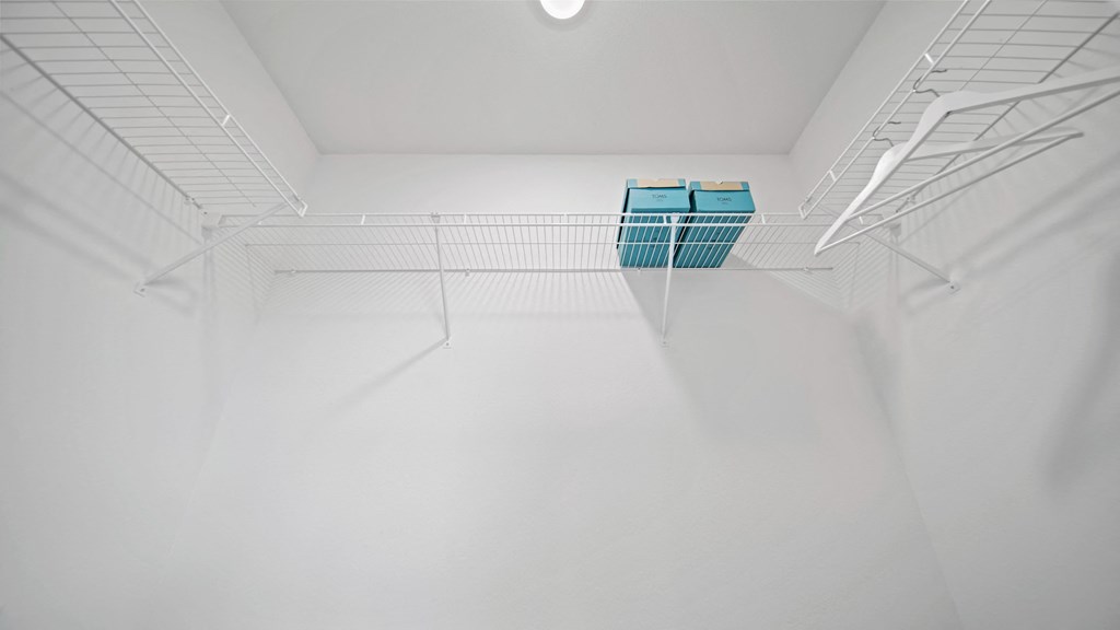 a walk in closet with a white ceiling and two blue bins on a wire rack